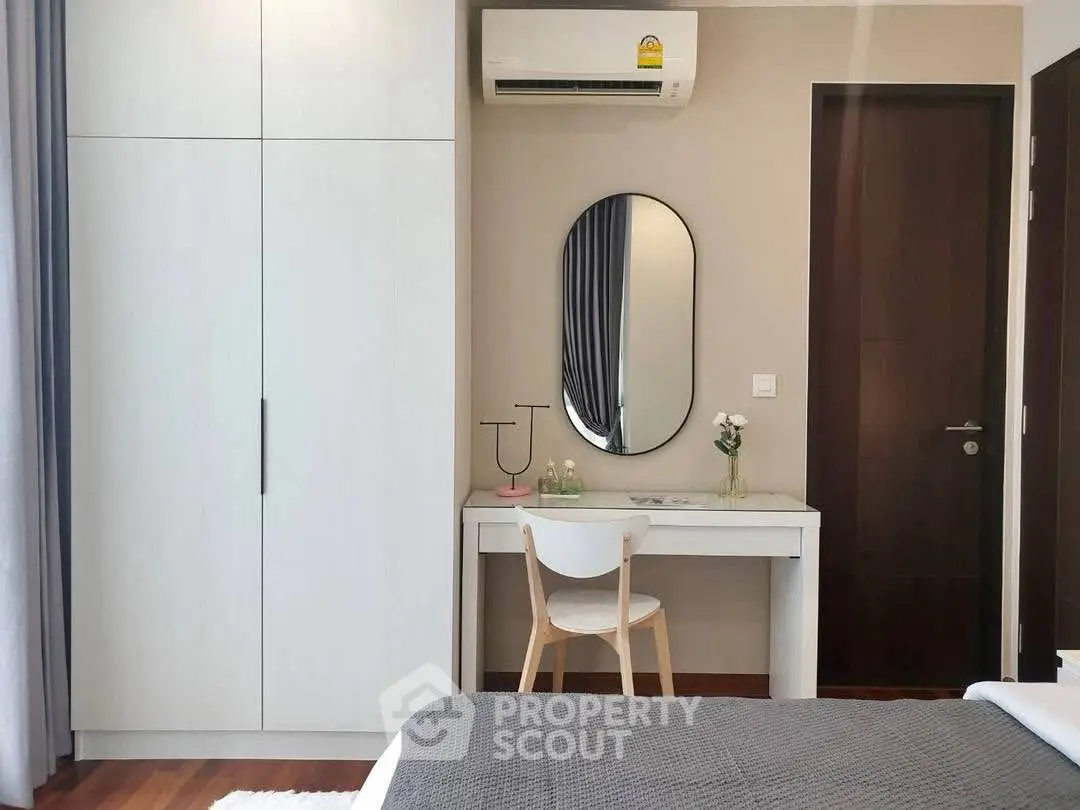 Modern bedroom with sleek furniture and air conditioning, featuring a stylish vanity and comfortable bed.