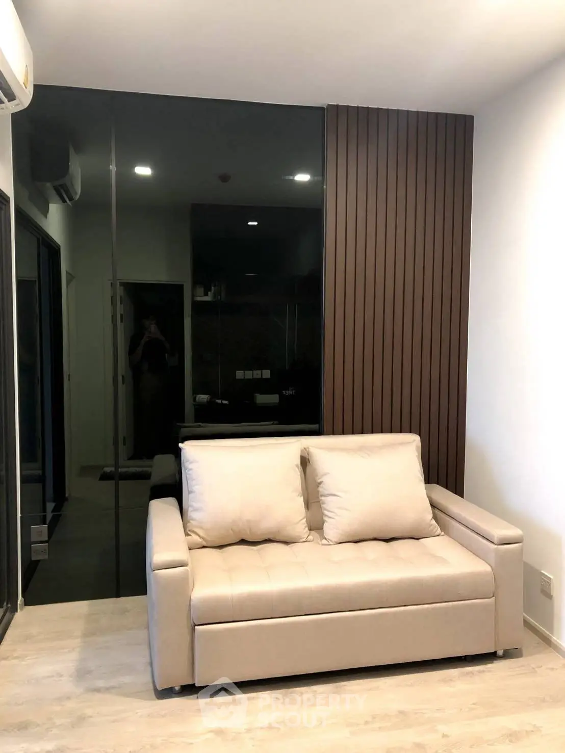 Modern living room with stylish beige sofa and sleek wooden paneling, perfect for urban living.