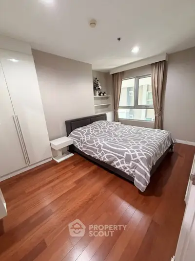 Spacious bedroom with modern decor and large window in a stylish apartment.