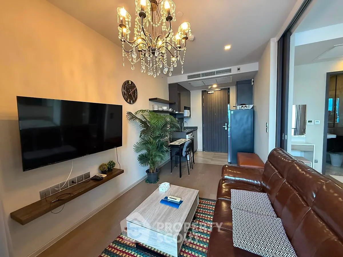 Stylish living room with leather sofa, chandelier, and modern decor in a contemporary apartment.