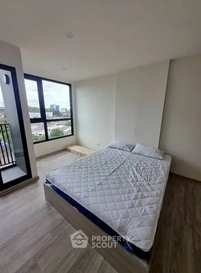 Spacious bedroom with large windows and city view, featuring a comfortable bed and modern flooring.