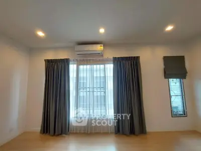 Spacious room with large windows and elegant curtains, featuring modern lighting and air conditioning.