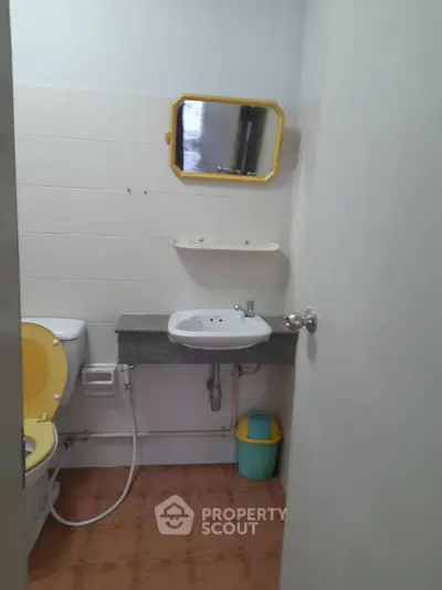 Compact bathroom with yellow accents and essential fixtures, ideal for small spaces.