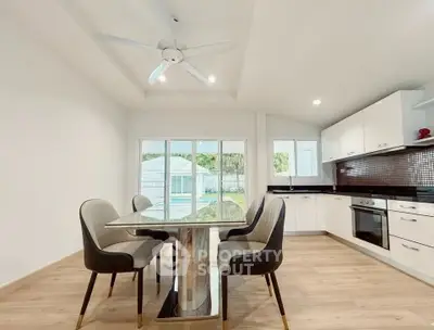 Modern kitchen with open layout and elegant dining area, featuring sleek cabinetry and pool view.
