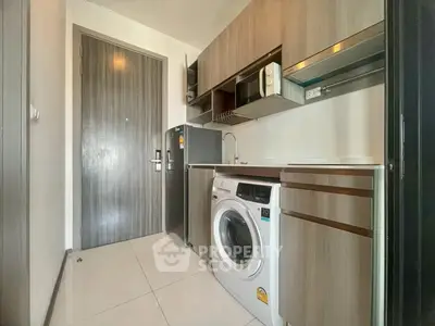 Modern compact kitchen with washing machine and microwave in sleek apartment.