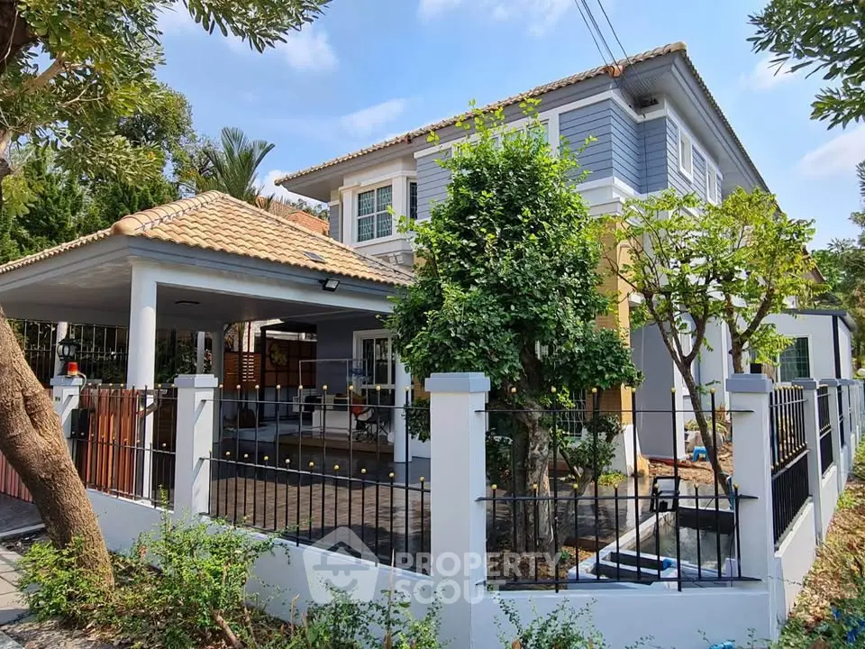 Charming two-story house with tiled roof, spacious garden, and modern fence in a serene neighborhood.