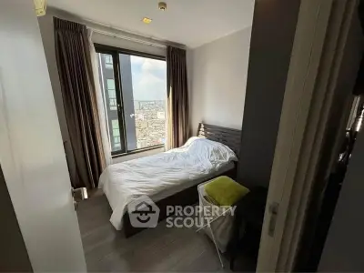 Cozy bedroom with city view, featuring large window and modern decor.