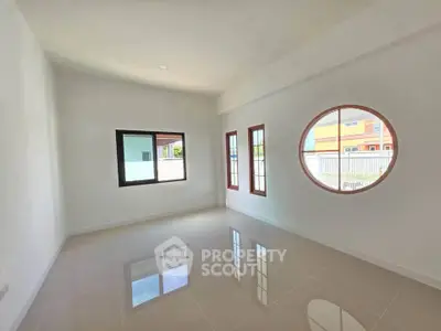 Bright empty room with unique round window and glossy tiled floor