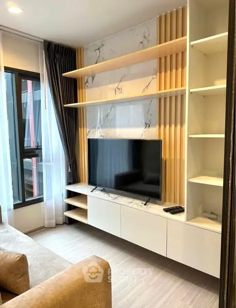 Modern living room with sleek TV unit and large window for natural light.