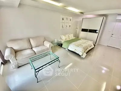 Spacious modern bedroom with cozy sofa and glass coffee table, perfect for relaxation and comfort.