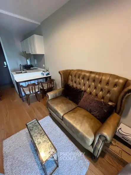 Cozy living room with vintage leather sofa and compact kitchen area, perfect for modern urban living.