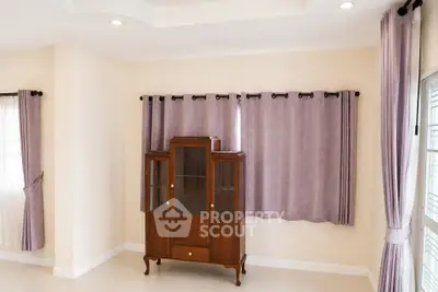 Spacious living room with elegant wooden cabinet and large windows with purple curtains.