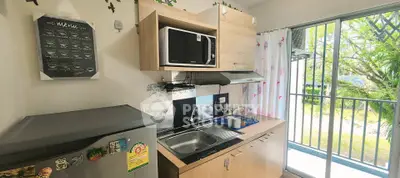 Charming compact kitchen with balcony view, featuring modern appliances and natural light.