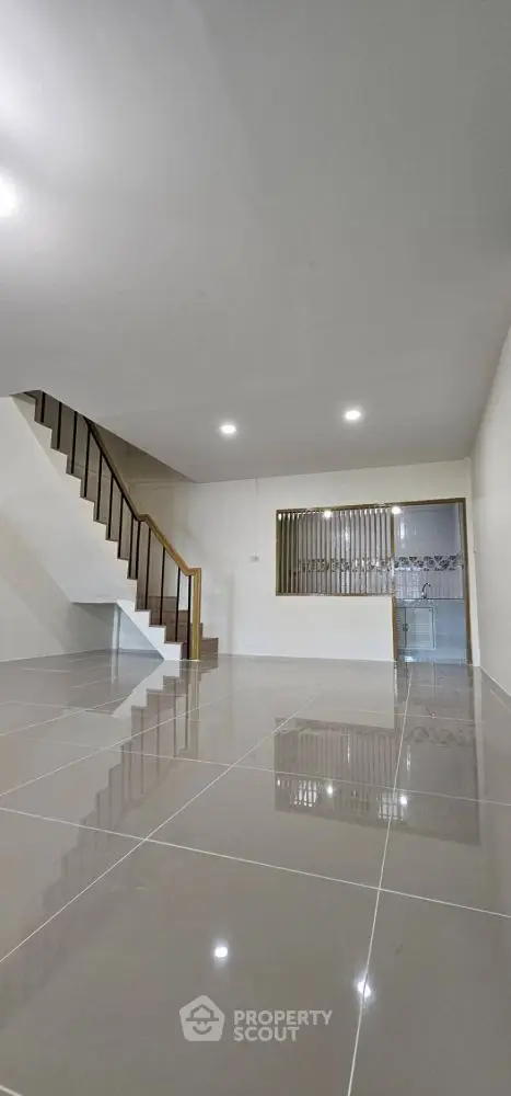 Spacious modern living room with sleek tile flooring and elegant staircase