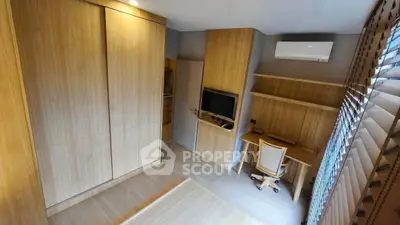 Modern study room with wooden furniture and built-in storage, featuring a sleek desk and air conditioning.