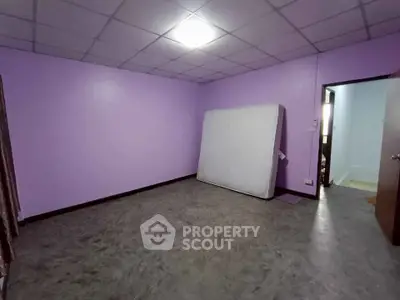 Spacious empty room with purple walls and a mattress, ideal for customization.