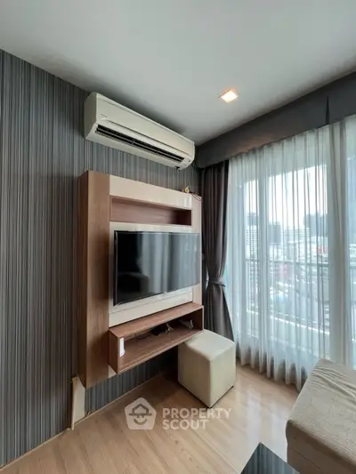 Modern living room with wall-mounted TV and air conditioning, featuring sleek design and city view.