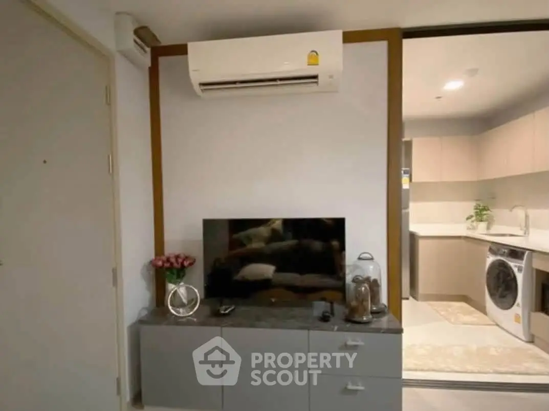 Modern living room with air conditioning and sleek kitchen appliances in a stylish apartment.