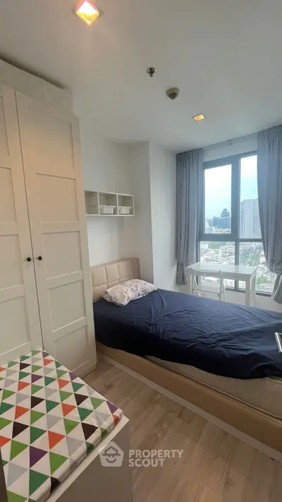 Cozy bedroom with city view, featuring a single bed, wardrobe, and natural light.