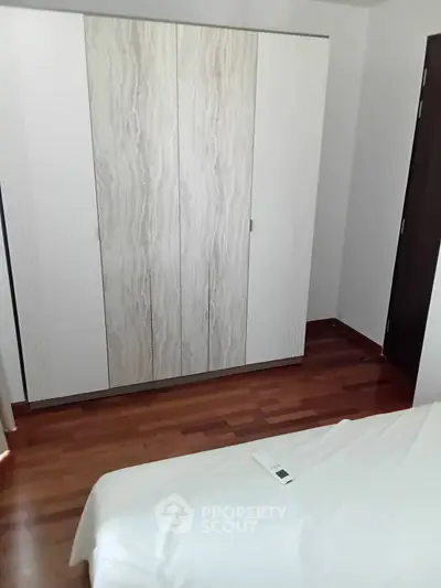 Modern bedroom with sleek wardrobe and wooden flooring, perfect for stylish living.