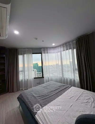 Modern bedroom with city view, featuring large windows and stylish decor.