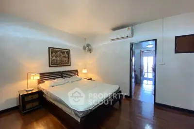 Spacious bedroom with wooden flooring and modern decor in a cozy apartment.