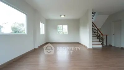 Spacious empty room with wooden flooring and large windows in modern home