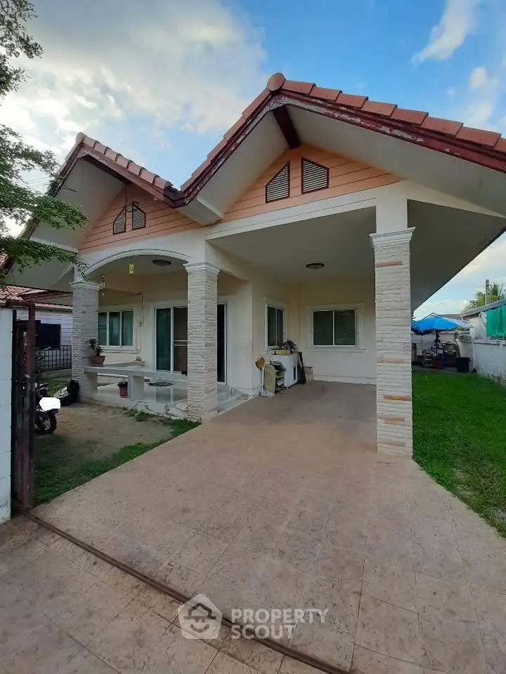 Charming single-story house with tiled driveway and lush green lawn, perfect for family living.