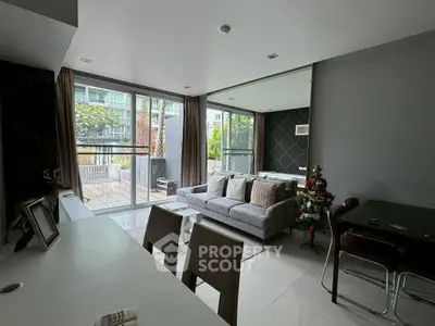 Modern living room with large windows and balcony access, featuring stylish decor and ample natural light.