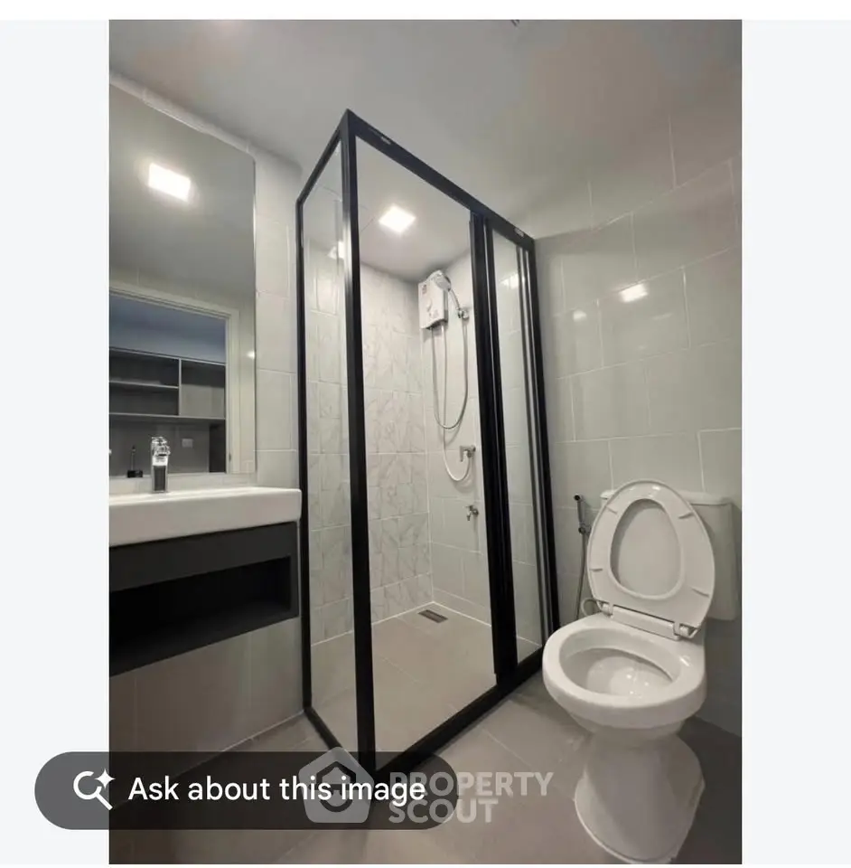 Modern bathroom with glass shower enclosure and sleek fixtures.