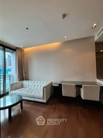 Modern living room with elegant sofa and city view, featuring hardwood floors and stylish furniture.