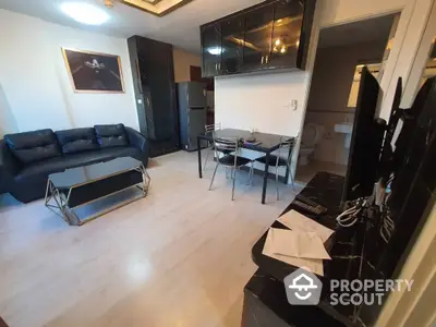 Modern living room with sleek black furniture and light wood flooring, featuring a cozy sofa and a glass dining table set.