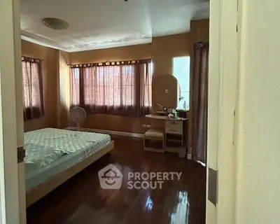 Cozy bedroom with wooden flooring and natural light