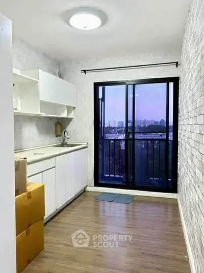 Bright kitchen with balcony view, featuring sleek white cabinets and modern design.