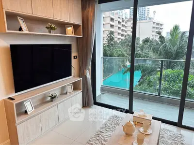 Modern living room with large TV, elegant decor, and balcony view of lush greenery and pool.