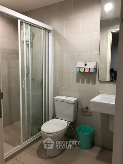 Modern bathroom with shower, toilet, and sink in a sleek tiled design.