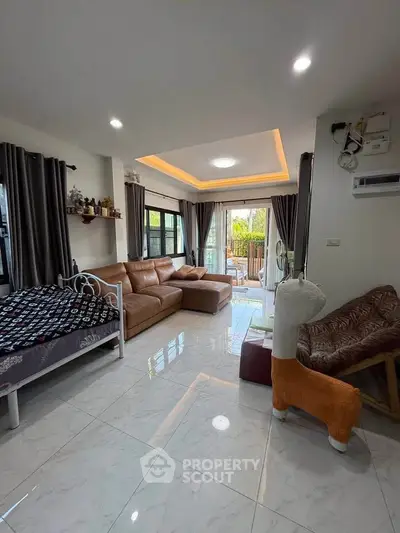 Spacious living room with modern decor and large windows opening to a balcony.