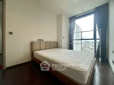 Modern bedroom with large window offering city view, featuring a minimalist design and natural light.