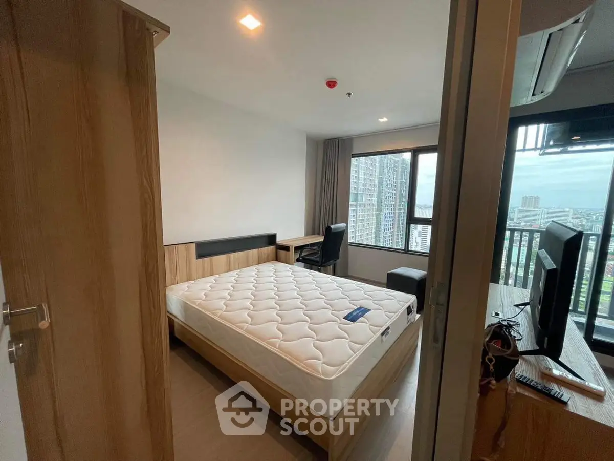 Modern bedroom with city view and balcony access in high-rise apartment