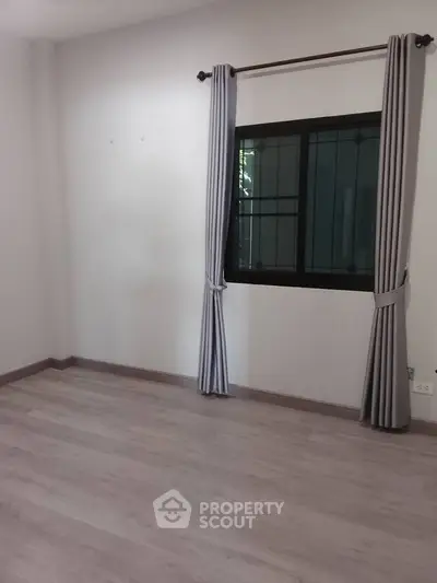 Spacious empty room with elegant curtains and large window, perfect for customization.