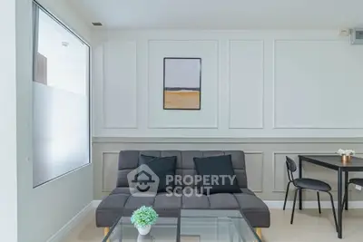 Modern living room with stylish sofa and glass coffee table in bright interior.