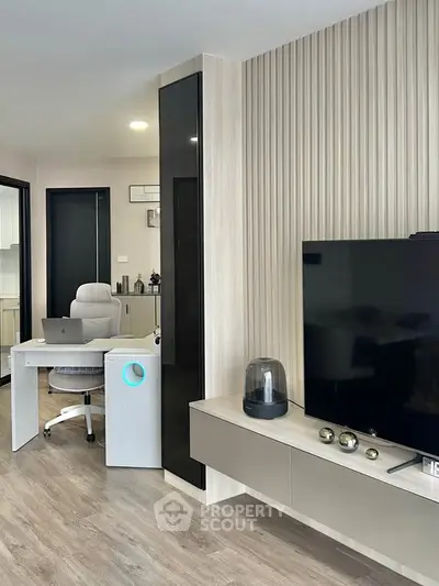 Modern living room with sleek TV setup and stylish workspace, featuring contemporary decor and wooden flooring.