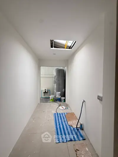 Under-construction utility room with exposed ceiling and paint supplies, ideal for customization.