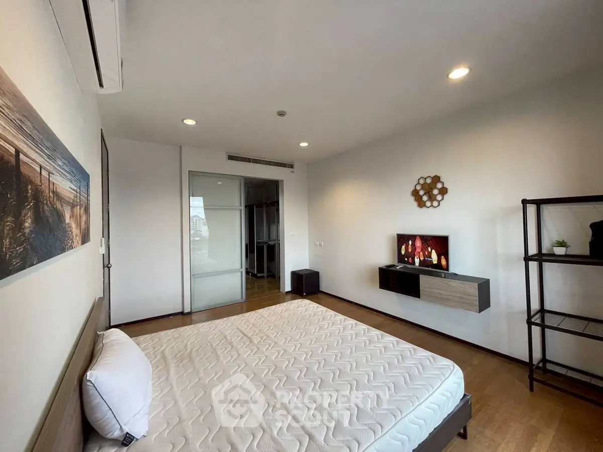 Modern bedroom with minimalist decor and wall-mounted TV