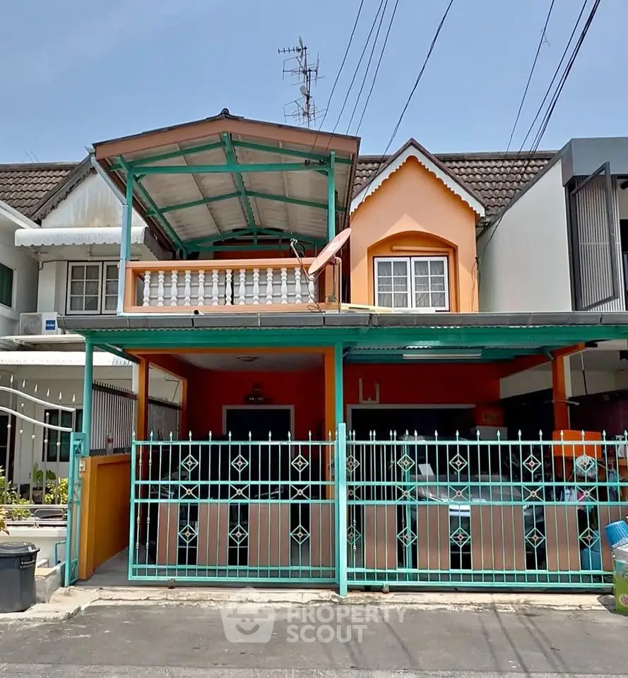 Charming two-story house with colorful facade and gated entrance in a suburban neighborhood.