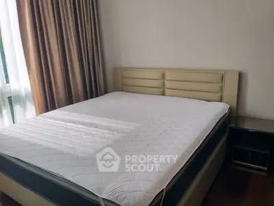 Spacious bedroom with large window and modern bed in a cozy apartment.
