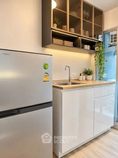 Modern kitchen with sleek cabinets and stainless steel fridge in a stylish apartment.