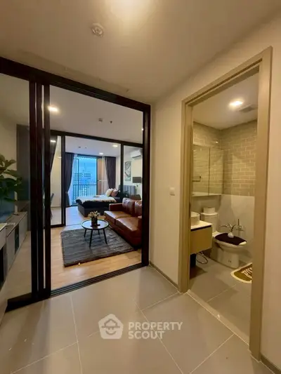 Modern apartment interior with living room and bathroom, featuring stylish decor and city view.