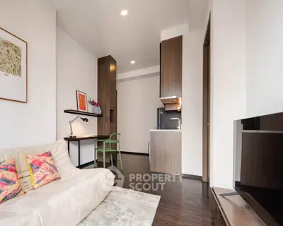 Modern living room with stylish decor and open kitchen layout, featuring a cozy sofa and sleek wooden flooring.