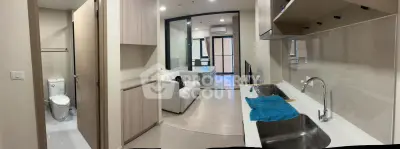 Modern apartment interior with open kitchen and cozy living area, featuring sleek design and ample natural light.